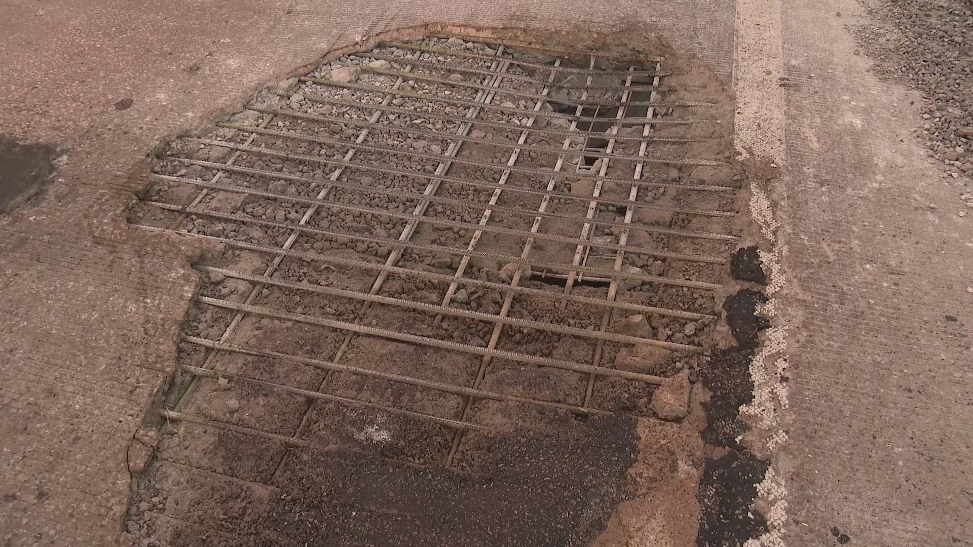 The road has crumbled away so much, the metal grid is visible in one of the largest potholes, and you can look down into the hole.