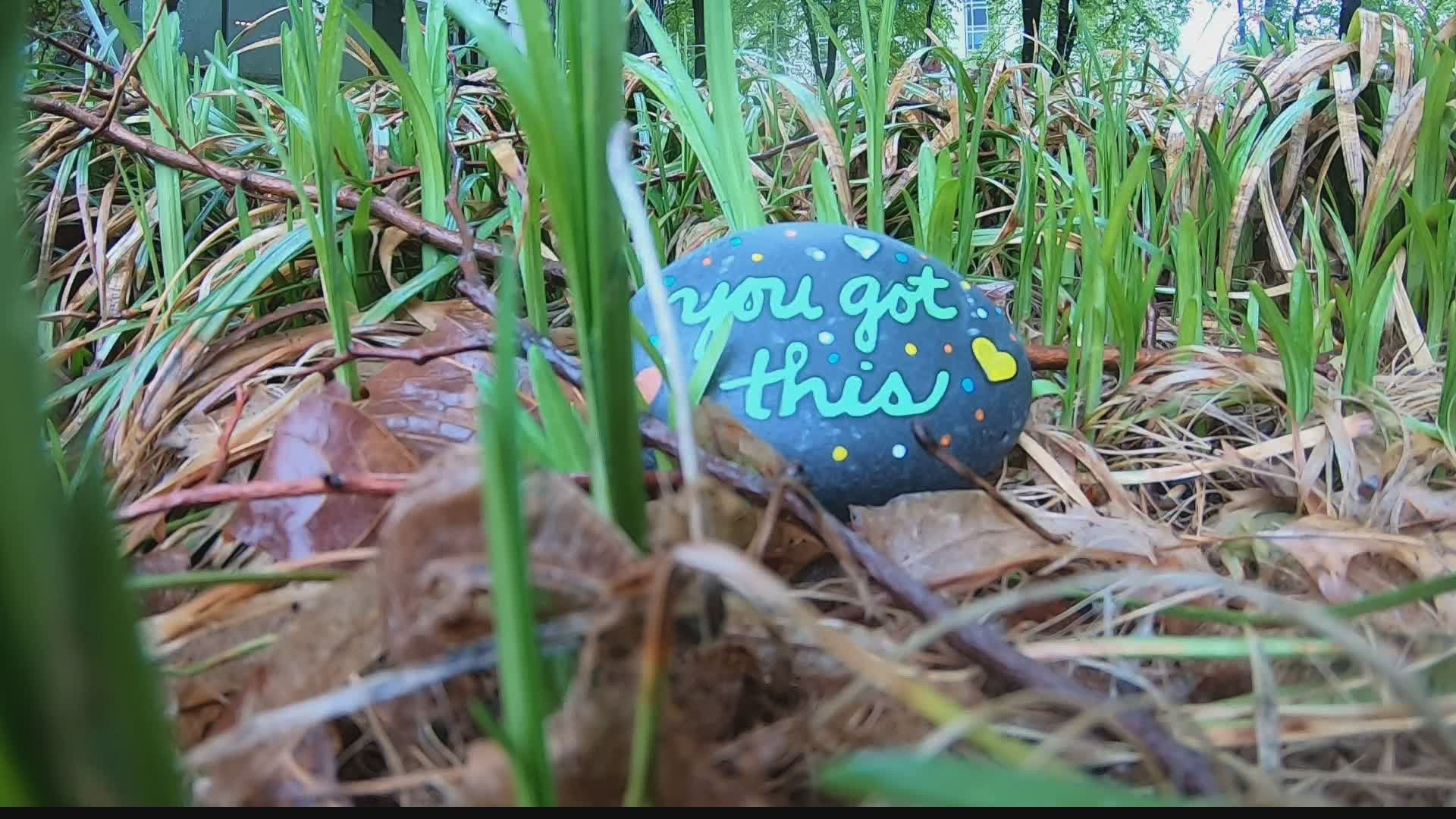 Woman paints rocks with positive messages on them