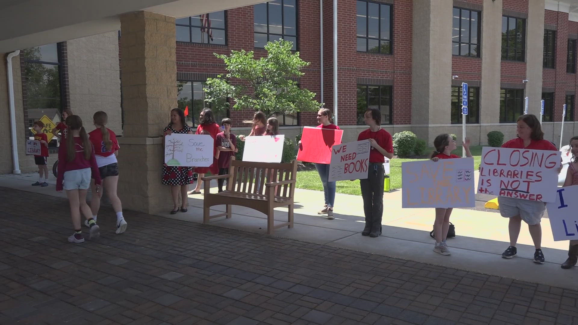 Nearly two dozen people protested Monday outside the newly renovated library at the Spencer Road branch in St. Peters.