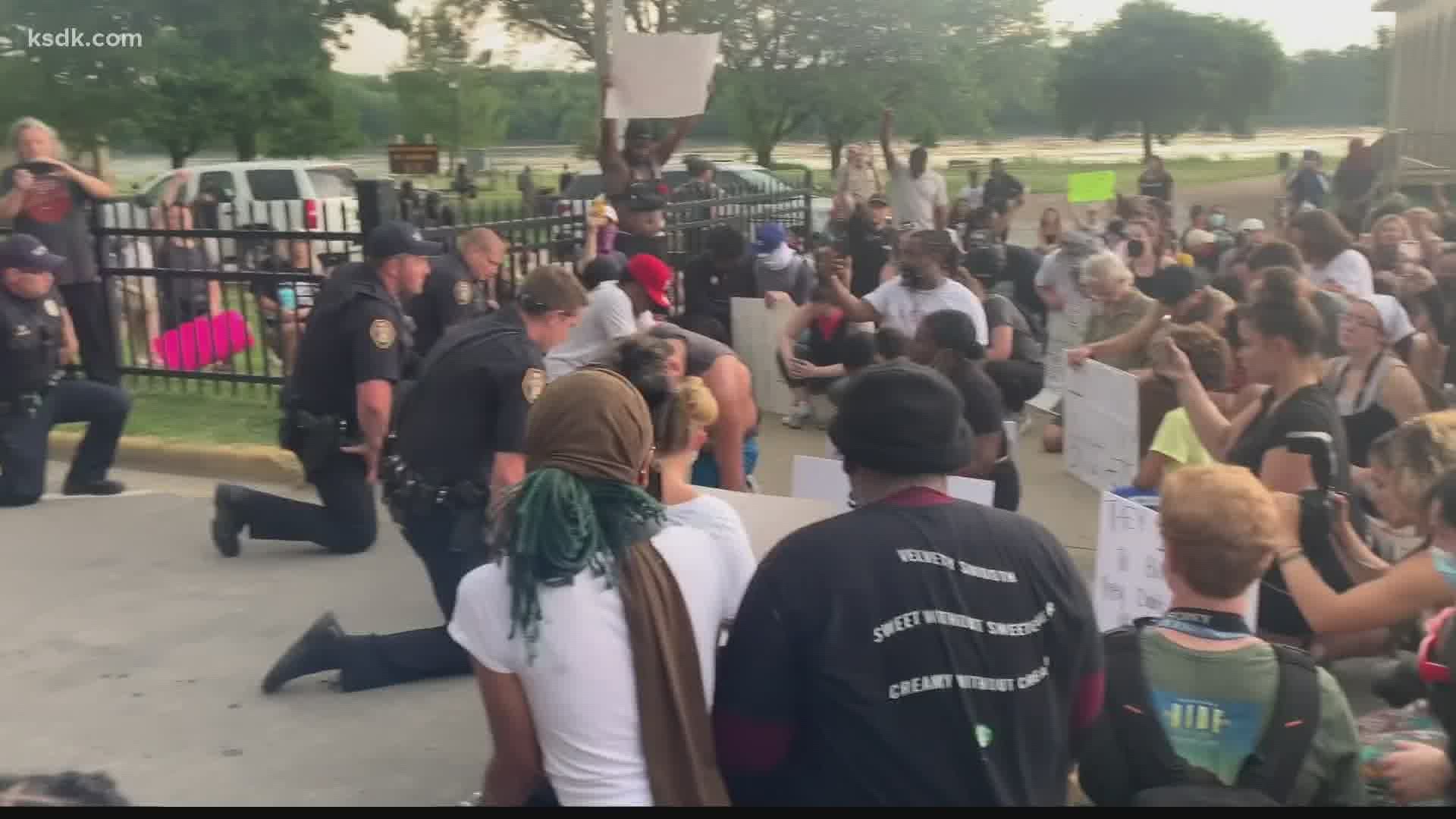 Police took a knee with some of the protesters during a march in St. Charles.