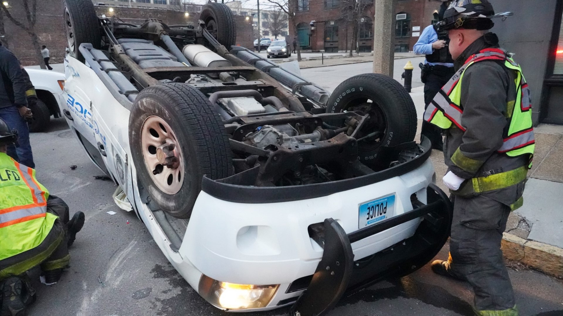 A St. Louis firefighter inspects an overturned St. Louis Police car after a crash with another vehicle.