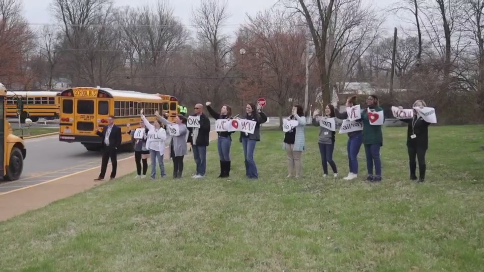 Teachers held up signs as buses left for an extended break